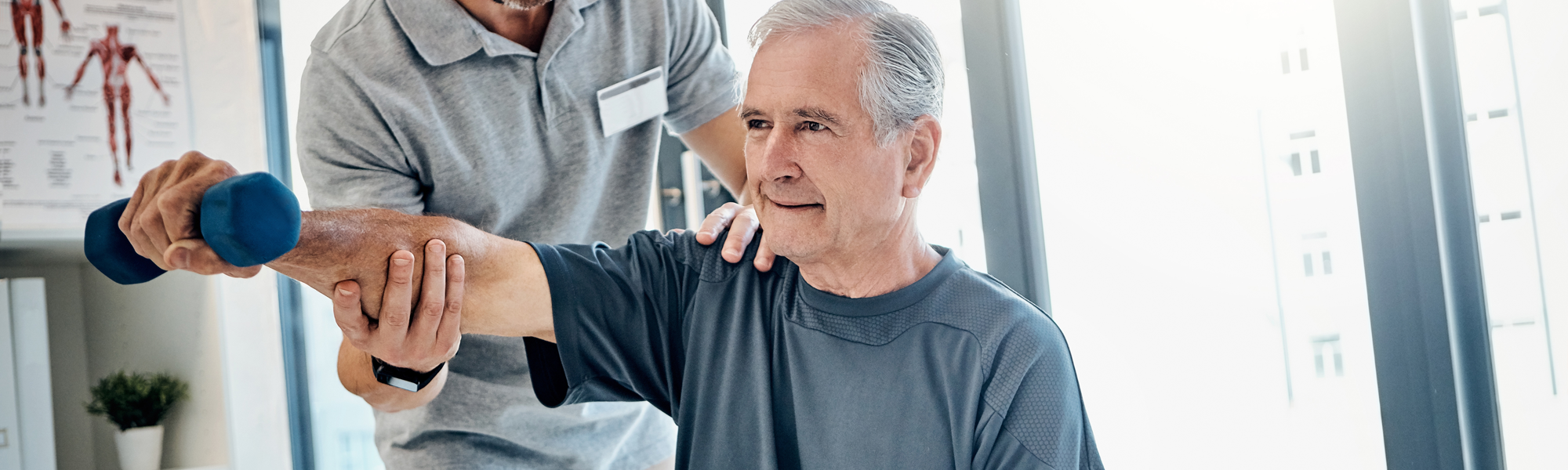 Physial therapist helping elderly man lift weight with arm extended straight out